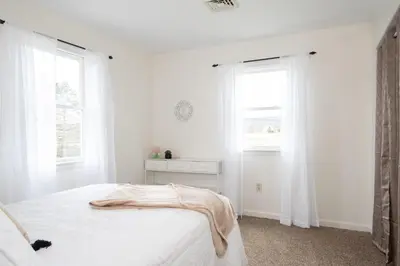 a white bedroom with a bed and two windows at Scenic View Lodging in Millerstown