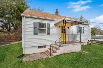 a small white house with a yellow door at White Clay Creek Cottage in Newark