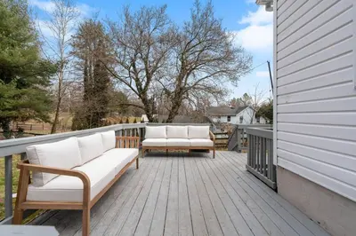 a deck with two white couches on a house at White Clay Creek Cottage in Newark