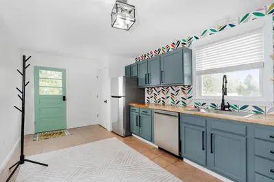 a kitchen with blue cabinets and a green door at White Clay Creek Cottage in Newark
