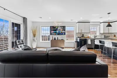 a living room with a black couch and a kitchen at Cityscape in Newark