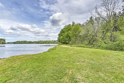 a grassy field next to a body of water at Game Room and Fire Pit Chic Pocono Pines Home! in Pocono Pines