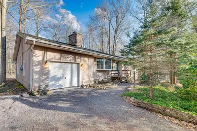 a house with a garage and a tree at Game Room and Fire Pit Chic Pocono Pines Home! in Pocono Pines