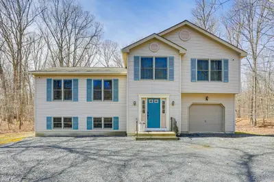 a white house with a blue door and a driveway at Forest-View Deck and Fire Pit Poconos Escape! in East Stroudsburg