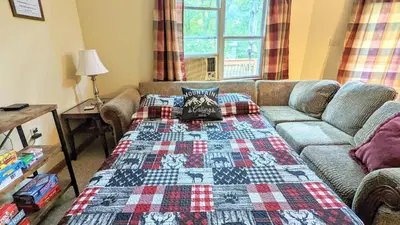 a living room with a couch and a blanket at The Bear Foot Lodge by AvantStay Game Room Deck BeachLake Access in Albrightsville
