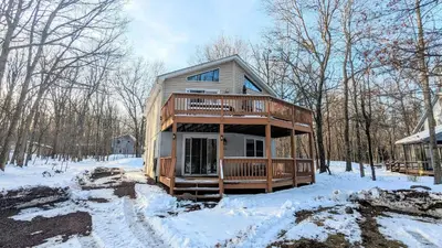 a cabin in the woods in the snow at The Bear Foot Lodge by AvantStay Game Room Deck BeachLake Access in Albrightsville