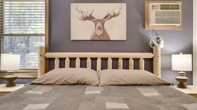 a bedroom with a bed with a deer head on the wall at Woodland Oasis by AvantStay Hot Tub Firepit Walk to Lake in Lake Harmony