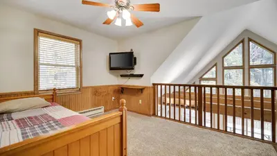 a bedroom with a bed and a ceiling fan at Woodland Oasis by AvantStay Hot Tub Firepit Walk to Lake in Lake Harmony
