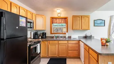 a kitchen with wooden cabinets and a black refrigerator at The Nest at Brier Crest by AvantStay Game Room Expansive Deck Fire Pit in Blakeslee