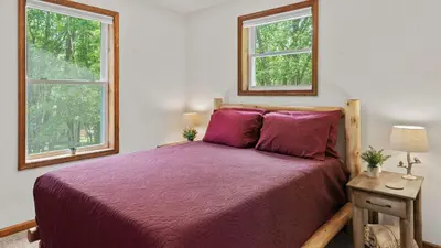 a bedroom with a bed with purple sheets and two windows at Maple Oasis by AvantStay Newly Built w Hot Tub Game Room Fire Pit in Blakeslee