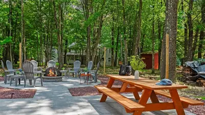 a picnic table and chairs and a fire place at Maple Oasis by AvantStay Newly Built w Hot Tub Game Room Fire Pit in Blakeslee