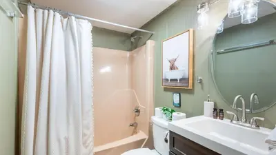 a bathroom with a sink and a toilet and a mirror at Lakeshore Oasis by AvantStay Private Beach Views Hot Tub Volleyball in Blakeslee