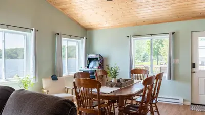 a dining room with a table and chairs and windows at The Lake Life by AvantStay Lakefront View Hot Tub in Arrowhead Lake