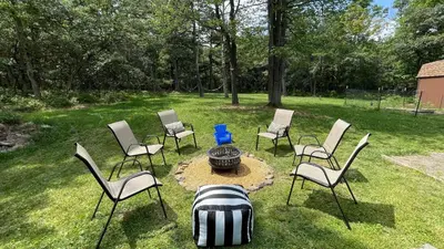 a group of chairs and a fire pit in a yard at The Wooden Nest by AvantStay Deck Big Yard w Hammocks Fire Pit in Long Pond