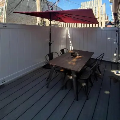 a wooden table and chairs with an umbrella on a deck at Fun Fishtown Rowhome - Sleeps 4 in Philadelphia