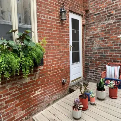 a porch with potted plants next to a brick wall at Bright & Modern Home with Patio in Philadelphia
