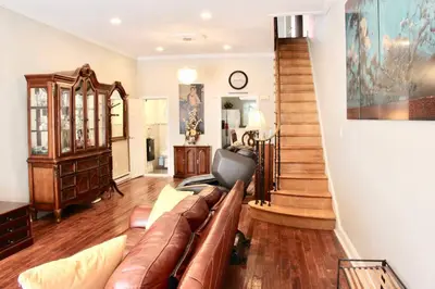 a living room with a brown leather couch and stairs at Walk to South Philly's Best Restaurants & Bars in Philadelphia