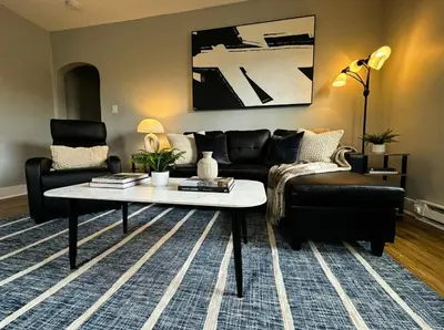 a living room with a black couch and a coffee table at Modern Cozy walk up with King Bed in Wilmington