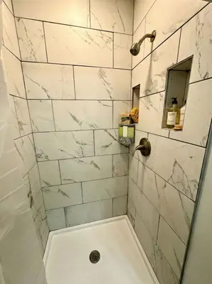 a bathroom with a shower with white marble tiles at Modern Cozy walk up with King Bed in Wilmington