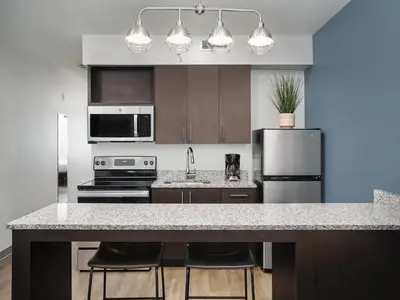 a kitchen with a counter with stools and a refrigerator at stayAPT Suites Harrisburg-Hershey in Harrisburg