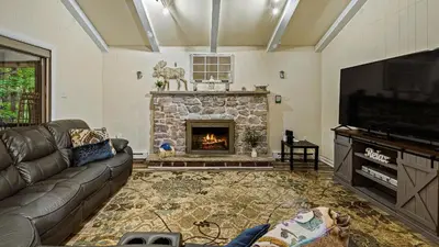 a living room with a couch and a fireplace at Frolic on Fern by AvantStay Enclosed Deck w Forest Views Bar in Blakeslee