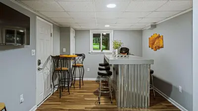 a kitchen with a bar with stools in it at Frolic on Fern by AvantStay Enclosed Deck w Forest Views Bar in Blakeslee