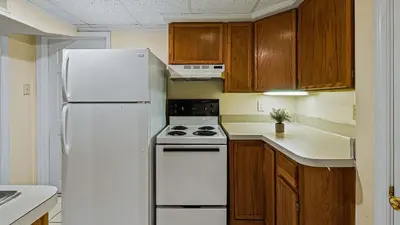 a kitchen with a white refrigerator and wooden cabinets at Frolic on Fern by AvantStay Enclosed Deck w Forest Views Bar in Blakeslee