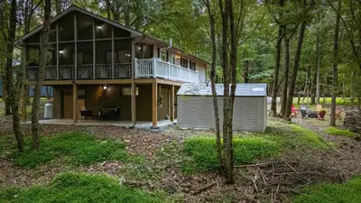 a large house with a balcony in the woods at Frolic on Fern by AvantStay Enclosed Deck w Forest Views Bar in Blakeslee