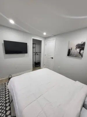 a white bedroom with a bed and a flat screen tv at Lake Luxe in Lake Ariel