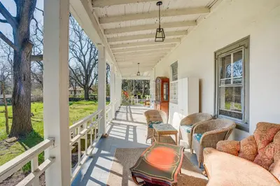 a porch of a house with chairs and a tree at Tranquil and Historic Estate Near Valley Forge in Eagleville