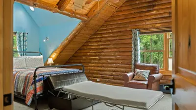 a log cabin bedroom with a bed and a chair at Bigwood Cabin Near Camelback Skiing Hot Tub Game Room Firepit Yard in Long Pond