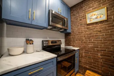 a kitchen with blue cabinets and a brick wall at Apt in the heart of Main Street in Stroudsburg