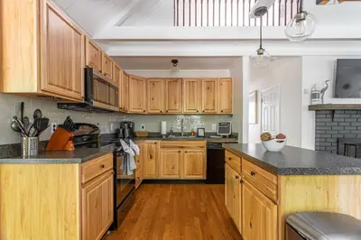 a kitchen with wooden cabinets and black counter tops at Updated 3 BDR Gas Fire Place BBQ in Albrightsville