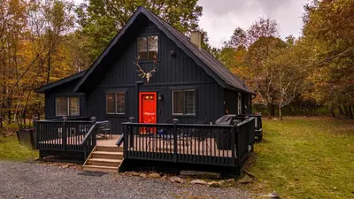 a black house with a red door in a yard at Updated 3 BDR Gas Fire Place BBQ in Albrightsville