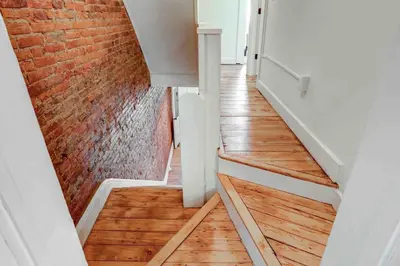 a staircase with wood floors and a brick wall at Beautiful Boho Villa on Vine in the heart of Lancaster in Lancaster
