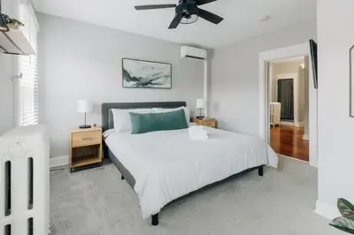 a white bedroom with a bed and a ceiling fan at Comfy renovated townhome - heart of Downtown Lancaster in Lancaster