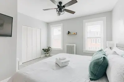 a bedroom with a white bed with a ceiling fan at Comfy renovated townhome - heart of Downtown Lancaster in Lancaster