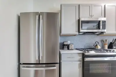 a stainless steel refrigerator in a kitchen with white cabinets at Fun & Funky 2BR in Downtown Princeton in Princeton