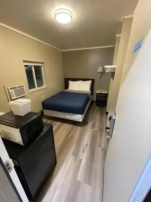 a bedroom with a bed with a blue bedspread at Scottish Inns - Middletown in Middletown