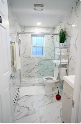 a white bathroom with a toilet and marble walls at Exquisite 3 Bedrooms in Newark