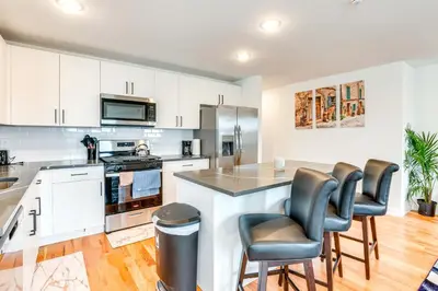 a kitchen with white cabinets and a island with bar stools at Modern Elizabeth Apartment about 1 Mi to Train Station in Elizabeth