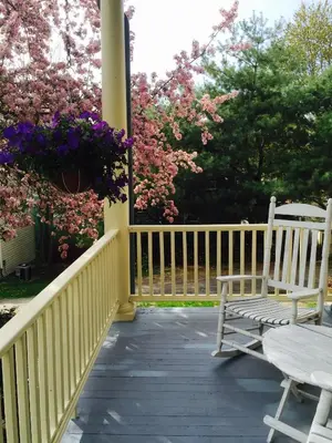 two chairs and a table on a porch with flowers at The Borland House Inn in Montgomery