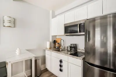 a kitchen with white cabinets and a stainless steel refrigerator at 73-819 New Studio UWS Doorman Gym in New York