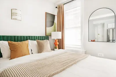 a bedroom with a bed with a green headboard and a mirror at 73-819 New Studio UWS Doorman Gym in New York