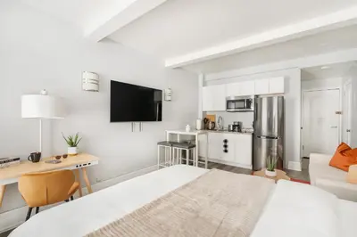 a white bedroom with a bed and a kitchen at 73-819 New Studio UWS Doorman Gym in New York