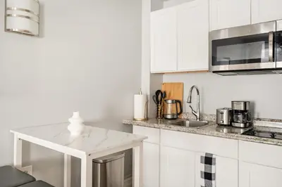 a white kitchen with white cabinets and a sink at 73-819 New Studio UWS Doorman Gym in New York