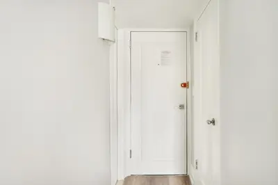 an empty hallway with a white door and wooden floor at 73-919 New Studio UWS Doorman Gym in New York