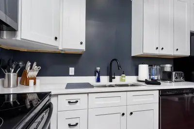 a kitchen with white cabinets and a sink at Flats on Front - Riverfront Gem Fast Wi-Fi 2F in Harrisburg