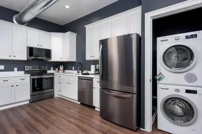 a kitchen with white cabinets and a stainless steel refrigerator at Flats on Front - Riverfront Gem Fast Wi-Fi 2F in Harrisburg