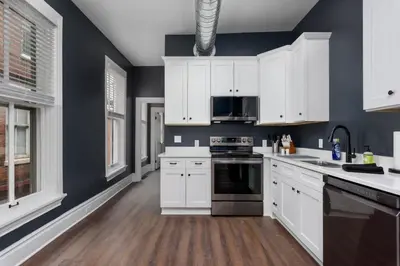 a kitchen with blue walls and white cabinets at Flats on Front - Riverfront Gem Fast Wi-Fi 2F in Harrisburg